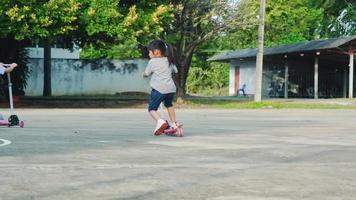 dos lindas niñas montando scooter en la carretera en el parque al aire libre el día de verano. los niños juegan al aire libre con scooters. ocio activo y deporte al aire libre para niños video