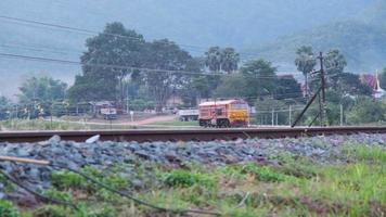 locomotive diesel corrono su binari per fermarsi alla stazione ferroviaria di lamphun. questa ripresa è stata girata al ponte bianco di tha chomphu durante il tramonto. video