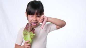 kinderen houden niet van groenten. klein meisje dat een hekel heeft aan het eten van groene salade. video