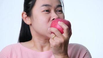 Asian woman holding an apple with a bite and smile showing strong teeth