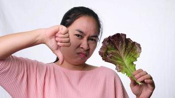 Asian woman hates fresh salad on white background in studio. Diet and Healthy food concept.