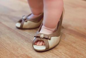 Little baby infant playing adult in mother's heel shoes photo