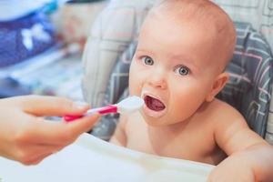 el pequeño bebé está comiendo su comida. alimentos para bebés, fórmula, cuidado del bebé foto