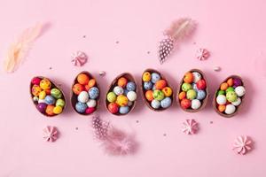 Chocolate easter eggs and decor flat lay for kids easter hunt egg concept on pink background. Sweets in the shape of an egg photo