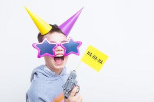 A cheerful boy in a funny outfit with a gun with the inscription ha ha ha for the April Fool's day. photo