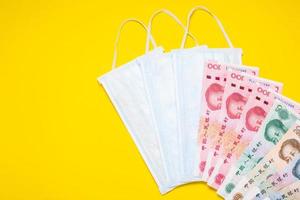 Chinese banknote  and new white mask on yellow. Mask is important but lack and very expensive in many country of Virus situation in 2020 photo