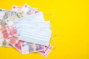 Chinese banknote  and new white mask on yellow. Mask is important but lack and very expensive in many country of Virus situation in 2020 photo