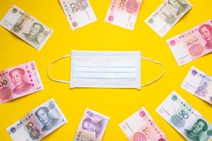 Chinese banknote  and new white mask on yellow. Mask is important but lack and very expensive in many country of Virus situation in 2020 photo