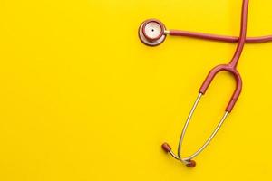 Red stethoscope on yellow background. For check heart or health check up concept photo