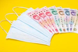 Chinese banknote and new white mask on yellow. Mask is important but lack and very expensive in many country of Virus situation in 2020 photo
