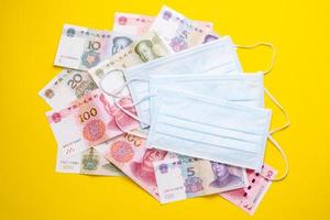 Chinese banknote  and new white mask on yellow. Mask is important but lack and very expensive in many country of Virus situation in 2020 photo