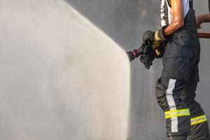 Firefighter spraying water from big water hose to prevent fire photo
