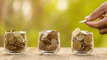 Coin in clear jar and piggy bank on green nature blur background. Money savings for home concept photo