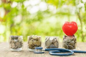 Blue stethoscope and jar of coin on wooden table. Money and financial checking concept photo