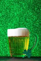 Mug of light beer with foam on a green background. Traditional Irish drink.