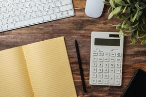 top view  wood table with calculator and notebook working desk at home photo