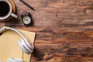 escritorio de trabajo de vista superior con auriculares y portátil, taza de café sobre fondo de mesa de madera foto