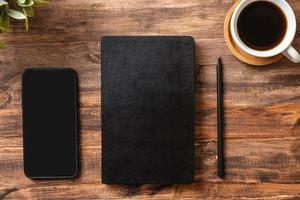 top view working desk with close notebook and mobile phone,coffee cup on wooden table background photo