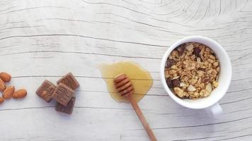 Top view of cereal breakfast in a bowl, honey, chocolate and almond nut on a table video