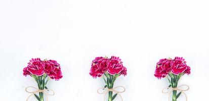 May mothers day photography - Beautiful blooming carnations bunch tied by bow isolated on a bright modern table, copy space, flat lay, top view, blank for text photo