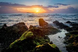 sunset landscape on the beach rocks in foreground photo