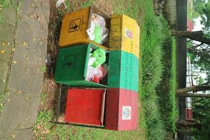 Editorial image of three green, yellow and red trash cans in the middle of the park photo