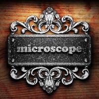 microscopio palabra de hierro sobre fondo de madera foto