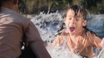 Asiatisches kleines Mädchen, das mit ihrer Schwester im Waldbach spielt. aktive erholung mit kindern am fluss im sommer. video