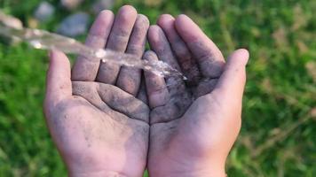 close-up das mãos da criança com salpicos de água no verão ensolarado ao ar livre. conceitos ambientais e de saúde
