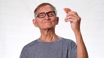 The old Asian man smiled happily showing his missing teeth and holding dentures in his hand. Health and dental care concept video