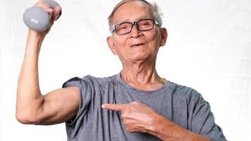 oudere aziatische man die halters opheft en armspieren toont. gezonde levensstijl video