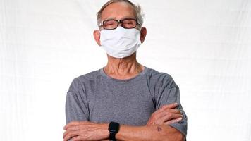 senior man bär en medicinsk ansiktsmask mot vit bakgrund. äldre man som bär mask för covid-19 förebyggande kampanj video