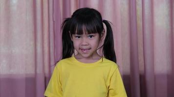 portrait d'une petite fille souriante heureuse sur un fond de rideau rose à la maison. video