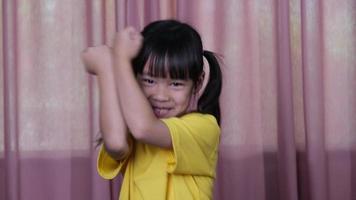 Cute little girl doing boxing moves and hitting the air for exercise indoors. Funny little boxing girl on a pink curtain background at home. video