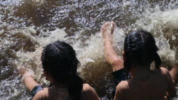 Aziatisch meisje dat met haar zus in de bosstroom speelt. actieve recreatie met kinderen op de rivier in de zomer. video