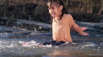 bambina asiatica che gioca nel ruscello della foresta con sua sorella. attività ricreative con bambini sul fiume in estate. video