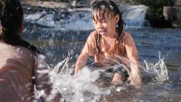 Asian little girl playing in the forest stream with her sister. Active recreation with children on river in summer. video