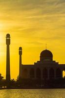 Songkhla Central Mosque in day to night with colorful skies at sunset and the lights of the mosque and reflections in the water in landmark landscape concept photo