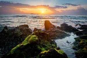 sunset landscape on the beach rocks in foreground photo