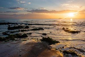 sunset landscape on the beach rocks in foreground photo