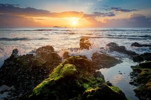 sunset landscape on the beach rocks in foreground photo