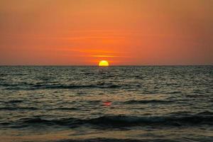 Bright sunset with large yellow sun under the sea surface photo