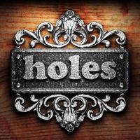 holes word of iron on wooden background photo