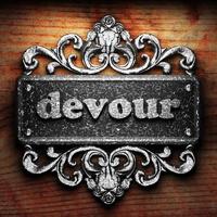 devour word of iron on wooden background photo