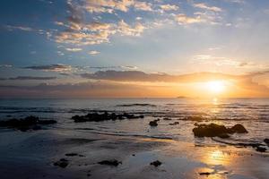 sunset landscape on the beach rocks in foreground photo