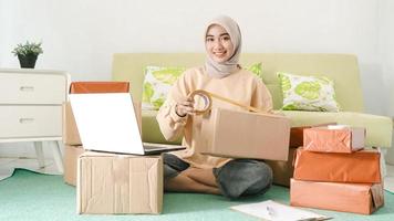 beautiful asian businesswoman packing customer orders in her room happily photo