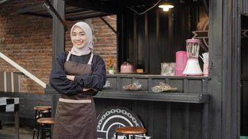 Beautiful Asian waitress with arms ready to serve at the cafe booth container photo