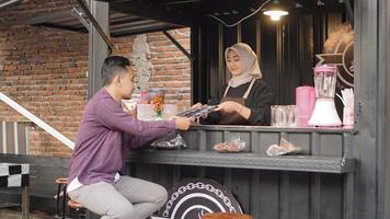 beautiful asian waitress giving a menu list to customers at the angkringan container booth photo