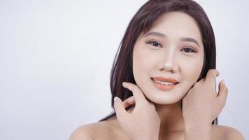 Chica asiática mostrando su rostro con maquillaje aislado sobre fondo blanco. foto