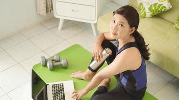 young woman finishes yoga practice playing laptop at home photo